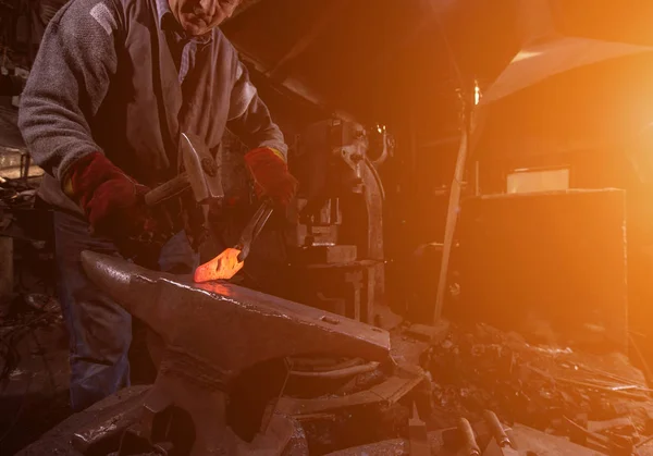 Blacksmith manually forging the molten metal with sunlight throu — Stock Photo, Image