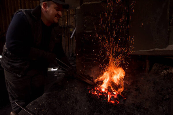 young traditional Blacksmith working with open fire