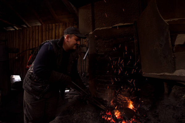 young traditional Blacksmith working with open fire