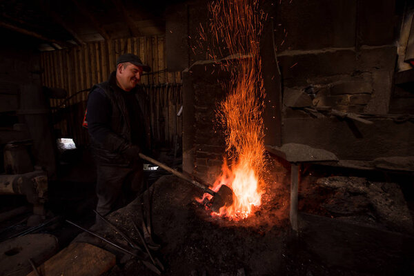 young traditional Blacksmith working with open fire