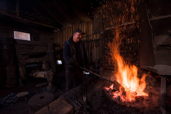 young traditional Blacksmith working with open fire