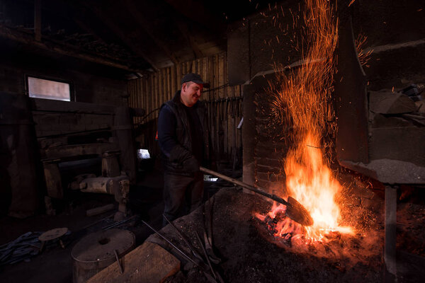 young traditional Blacksmith working with open fire
