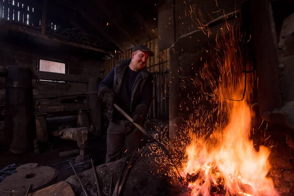 Giovane fabbro tradizionale che lavora con il fuoco aperto — Foto Stock