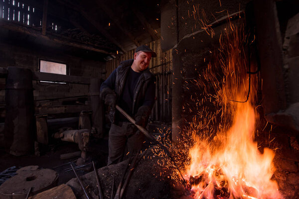 young traditional Blacksmith working with open fire