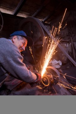 Demirci metal ürünlerini parlatıyor.