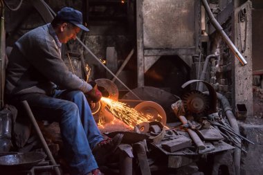 Demirci metal ürünlerini parlatıyor.
