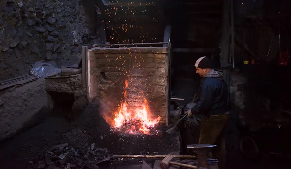 Νεαρός παραδοσιακός σιδεράς που εργάζεται με ανοιχτή φωτιά — Φωτογραφία Αρχείου