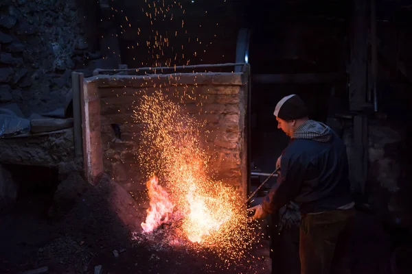 Jovem Blacksmith tradicional trabalhando com fogo aberto — Fotografia de Stock