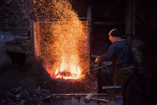 Giovane fabbro tradizionale che lavora con il fuoco aperto — Foto Stock