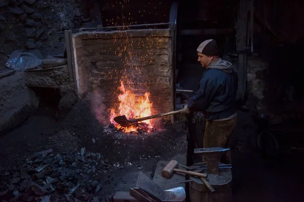 Joven Blacksmith tradicional trabajando con fuego abierto —  Fotos de Stock