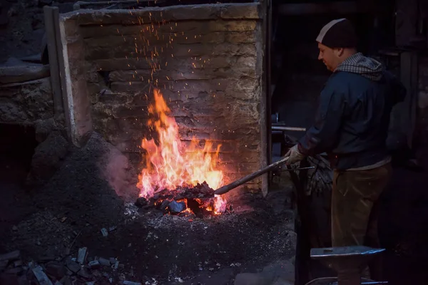 Joven Blacksmith tradicional trabajando con fuego abierto —  Fotos de Stock