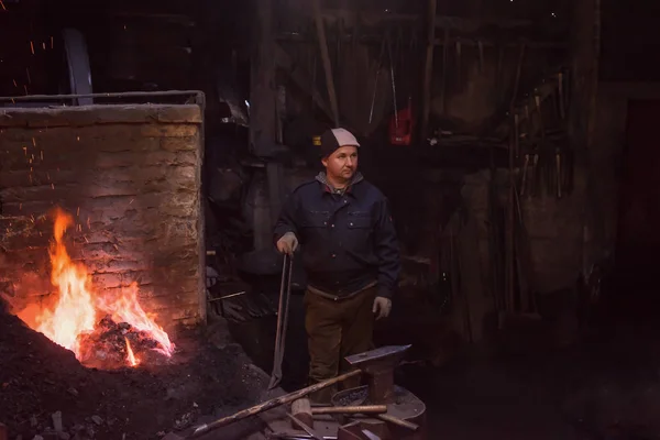 Jovem Blacksmith tradicional trabalhando com fogo aberto — Fotografia de Stock