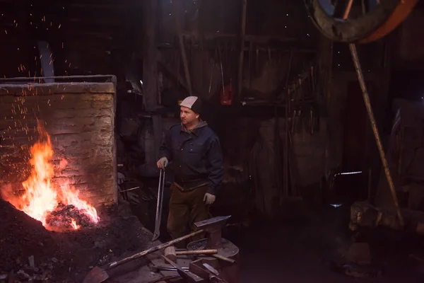 Jovem Blacksmith tradicional trabalhando com fogo aberto — Fotografia de Stock