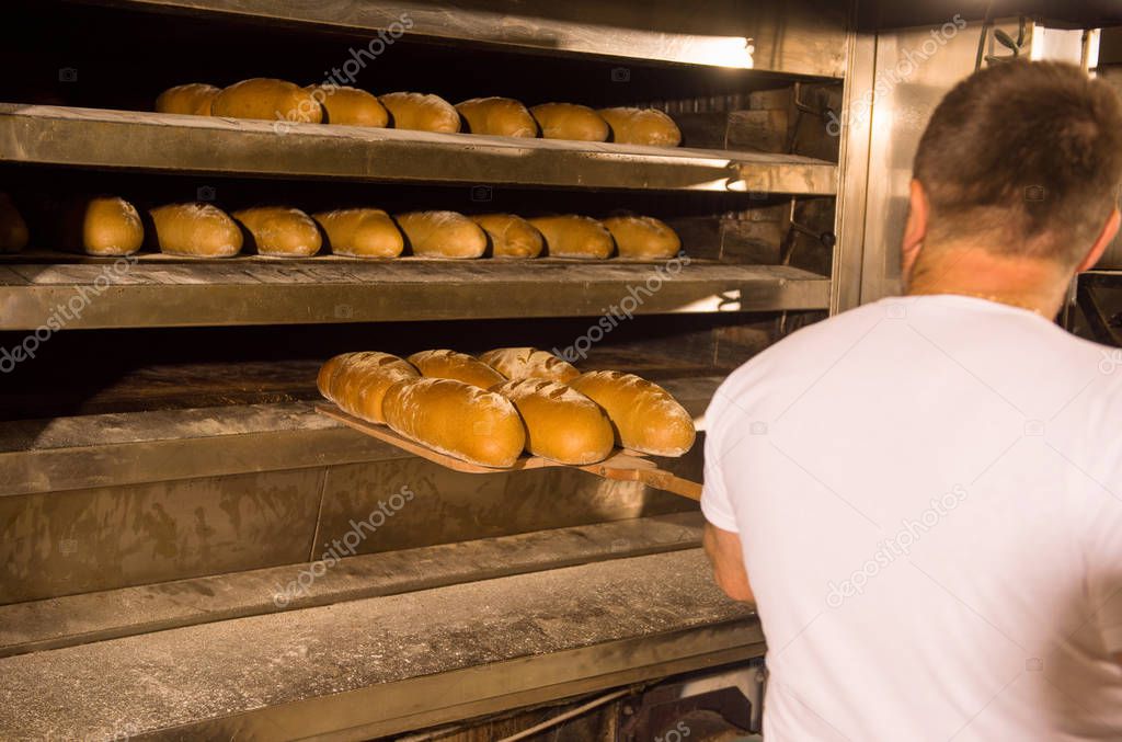 bakery worker taking out freshly baked breads