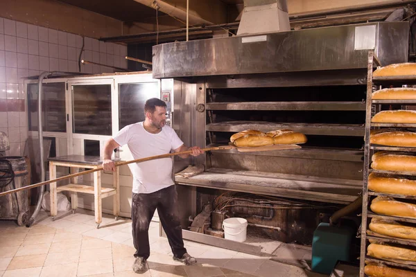 Trabalhador padaria tirando pães recém-assados — Fotografia de Stock