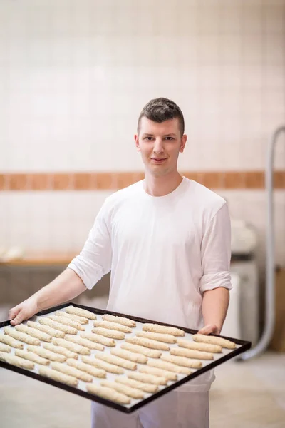 Um padeiro jovem segurando produto cru de massa branca — Fotografia de Stock