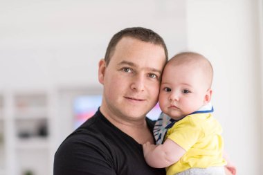 evde pencereyakınında bebek tutan genç baba