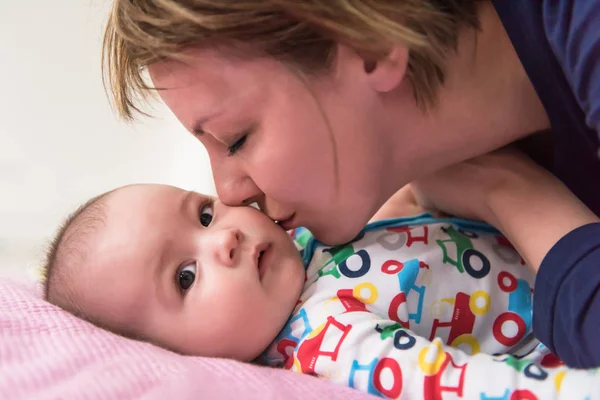 Jovem mãe beijando seu bebê pequeno bonito — Fotografia de Stock