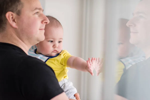 Junger Vater hält Baby zu Hause am Fenster — Stockfoto