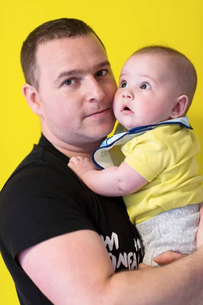 Retrato de feliz jovem pai segurando bebê isolado no amarelo — Fotografia de Stock