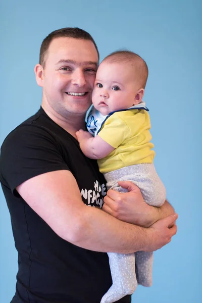 Portret van gelukkige jonge vader Holding baby geïsoleerd op blauw — Stockfoto