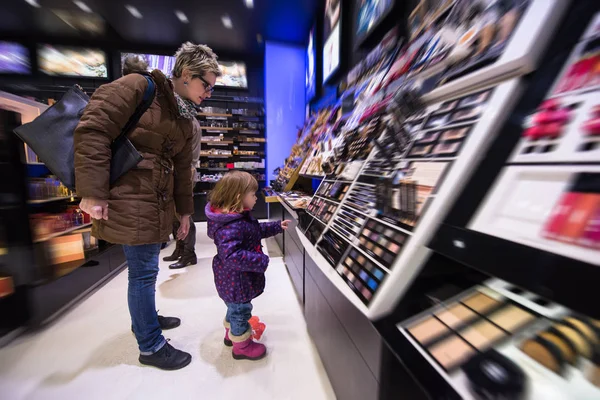 Joven madre y su hijita comprando maquillaje —  Fotos de Stock