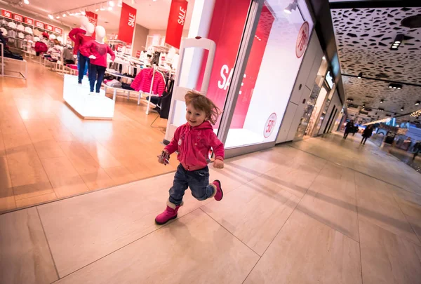 Petite fille courir à travers le centre commercial — Photo