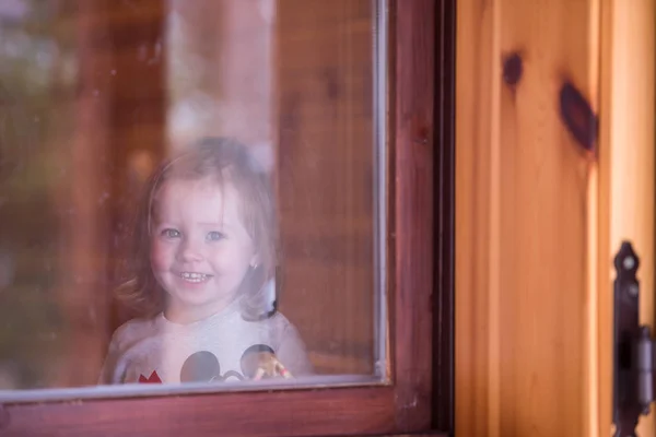 Kis aranyos lány játszik az ablak közelében — Stock Fotó