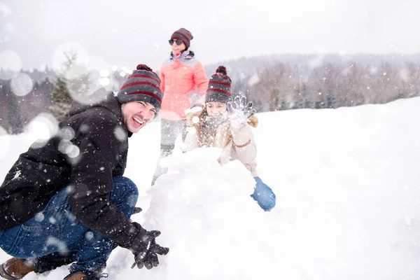 Grupo de jovens fazendo um boneco de neve — Fotografia de Stock