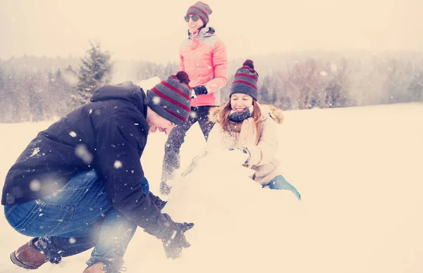 Grupo de jovens fazendo um boneco de neve — Fotografia de Stock