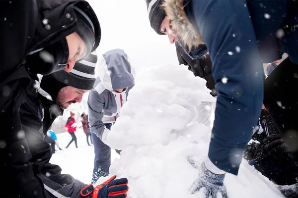 Grupo de jóvenes haciendo un muñeco de nieve —  Fotos de Stock