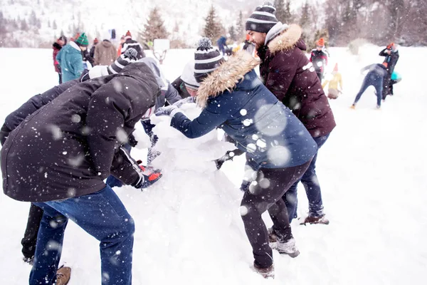 Groep jongeren die een sneeuwpop maken — Stockfoto