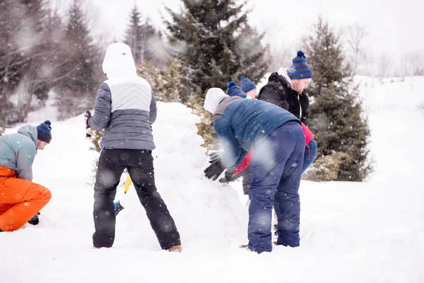Groep jongeren die een sneeuwpop maken — Stockfoto