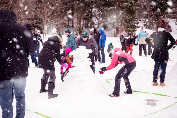 Grupo de jóvenes haciendo un muñeco de nieve — Foto de Stock