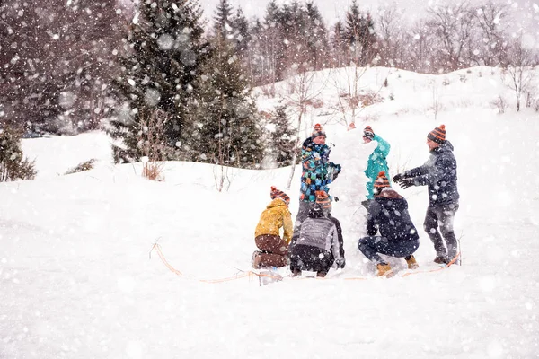 Група молодих людей, що роблять сніговика — стокове фото