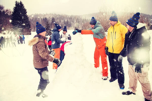 Grupo de jovens fazendo um boneco de neve — Fotografia de Stock