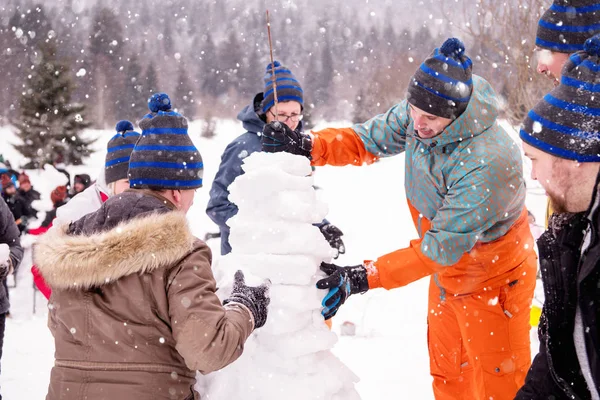 Groep jongeren die een sneeuwpop maken — Stockfoto