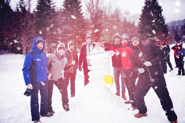 Груповий портал молодих людей, які позують зі сніговиком — стокове фото