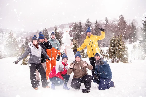 Gruppenporträt junger Leute, die mit Schneemann posieren — Stockfoto