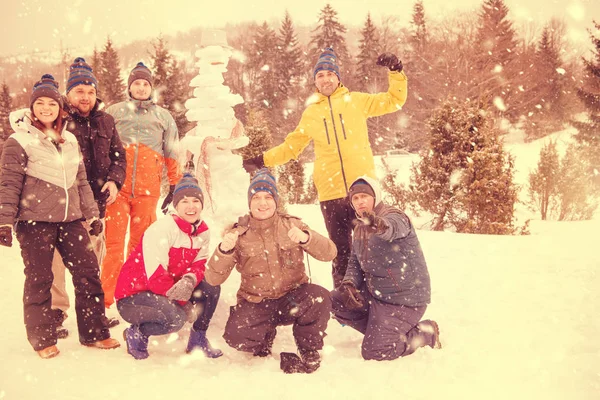 Groupe de jeunes posant avec bonhomme de neige — Photo