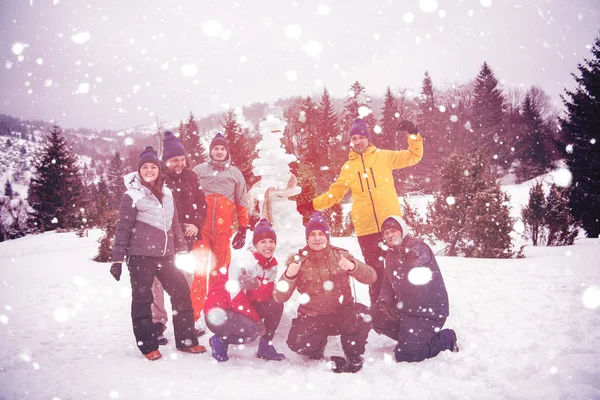 Groupe de jeunes posant avec bonhomme de neige — Photo