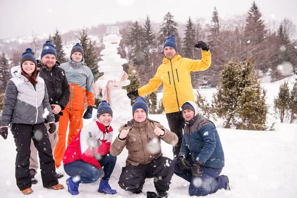 Grupo portait de jovens posando com boneco de neve — Fotografia de Stock
