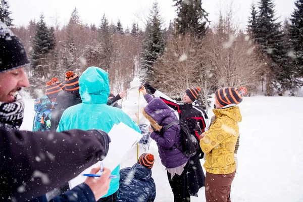 Jóvenes midiendo la altura del muñeco de nieve terminado — Foto de Stock