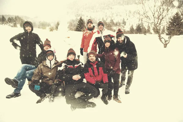 Group portait of young people posing with snowman — Stock Photo, Image