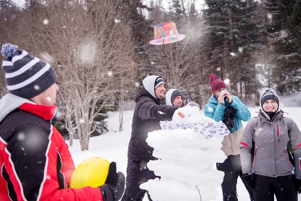 Groep jongeren die een sneeuwpop maken — Stockfoto