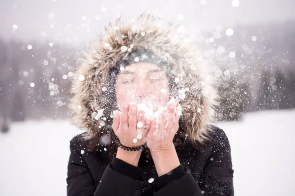 Giovane donna che soffia neve in un giorno nevoso — Foto Stock