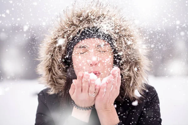 Jeune femme soufflant de la neige le jour neigeux — Photo