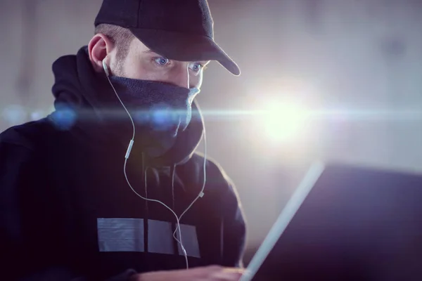 Young talented hacker using laptop computer while working in dar — Stock Photo, Image