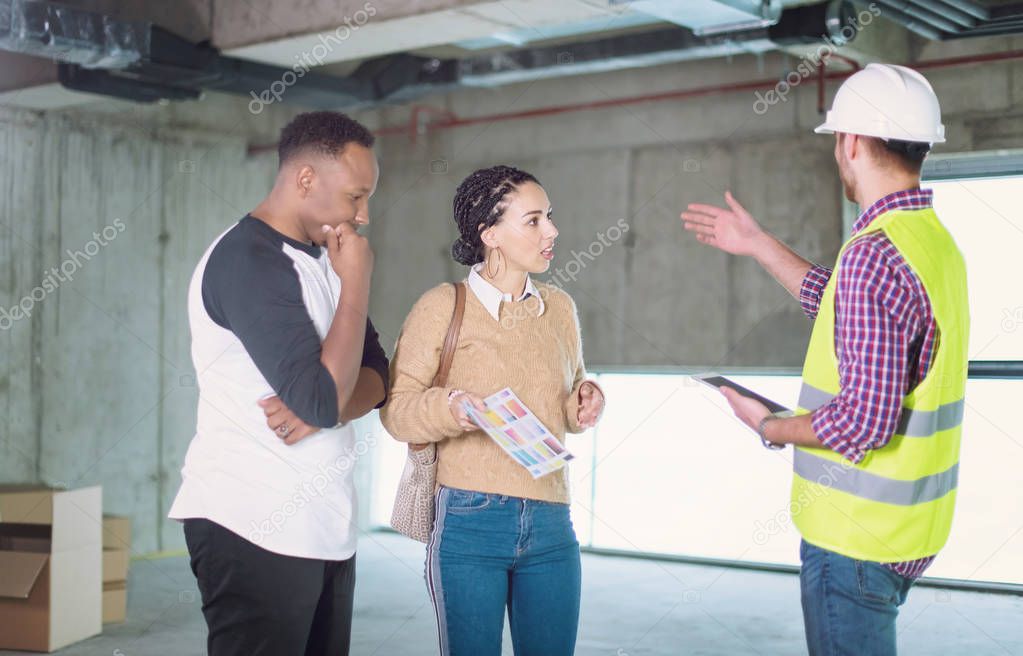 architect showing house design plans to a young multiethnic coup