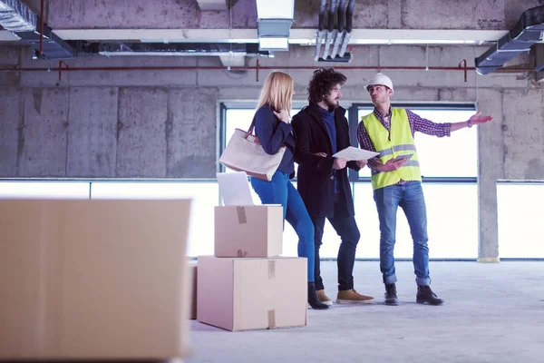 Arquiteto mostrando planos de design de casa para um jovem casal — Fotografia de Stock